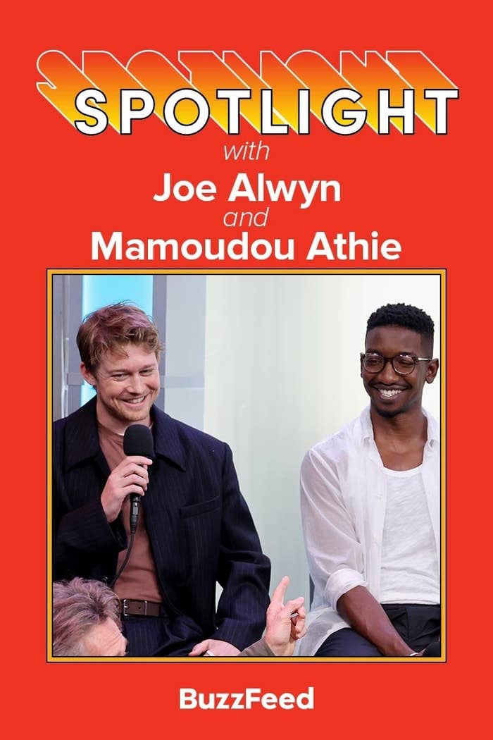 Spotlight interview with Joe Alwyn, in a dark collared outfit, and Mamoudou Athie, in a casual white shirt, by BuzzFeed