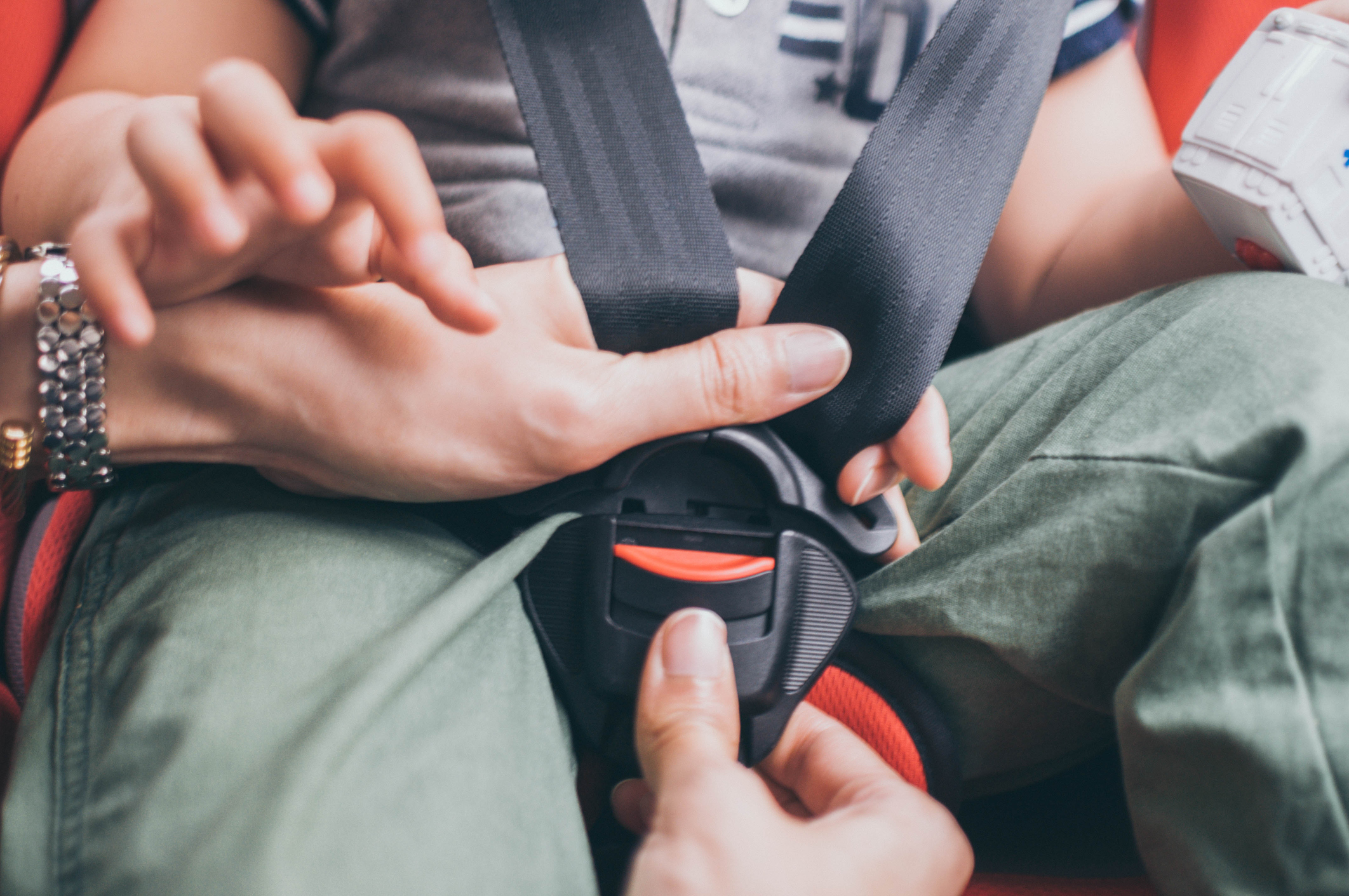 A parent buckling a child into the car seat.