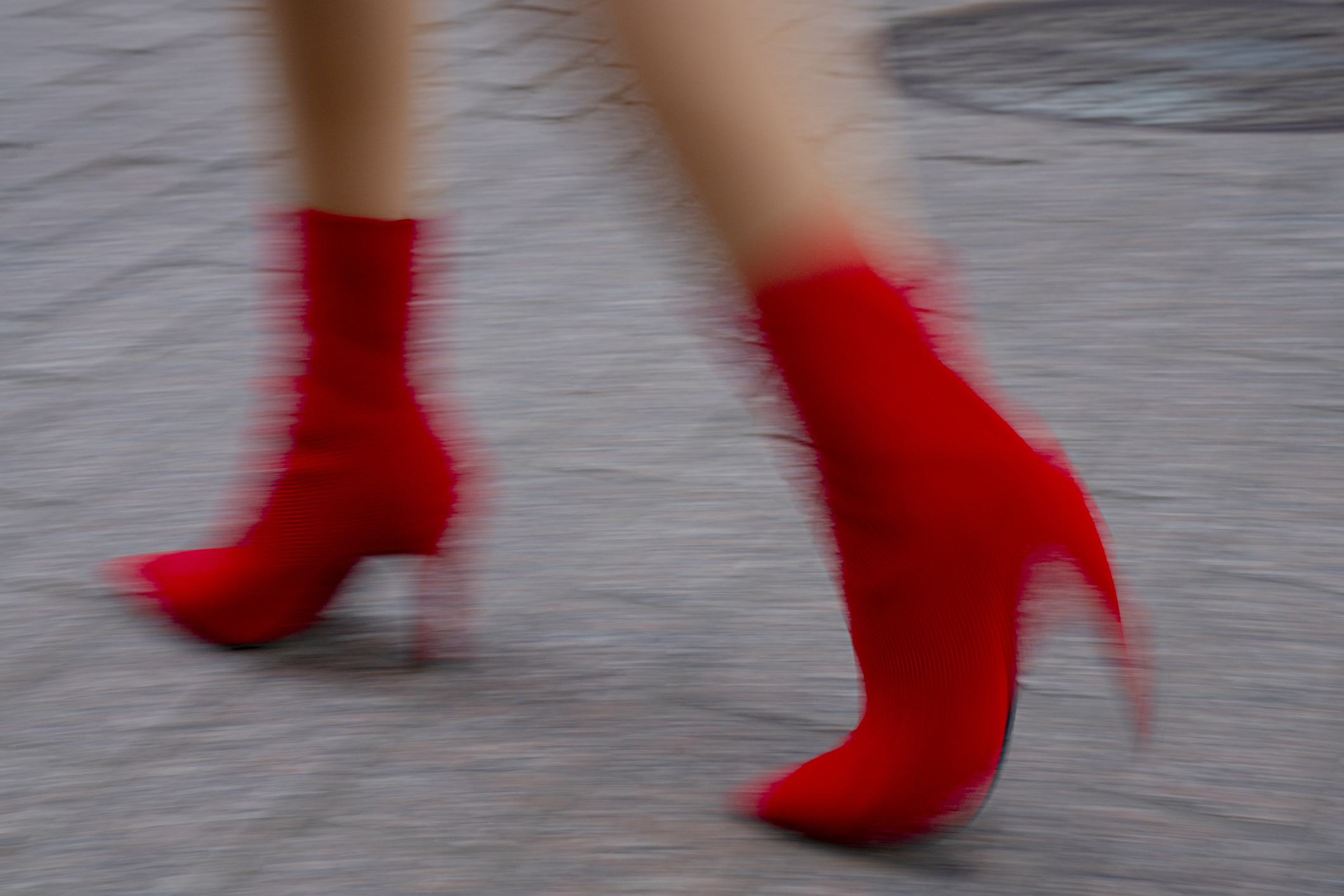 Blurred image of a person walking wearing high-heeled red boots