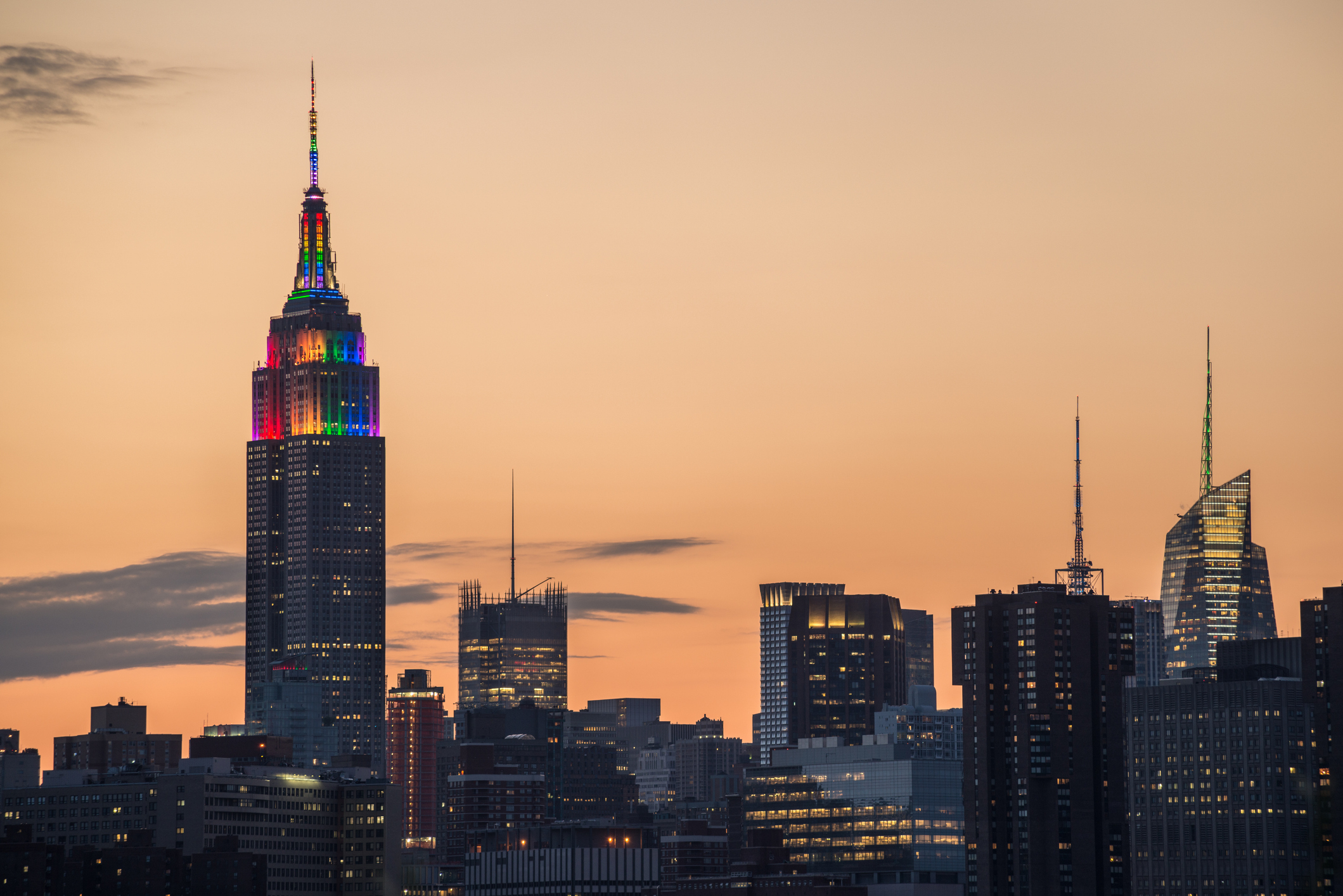 New York City skyline at dusk with the Empire State Building lit up in rainbow colors