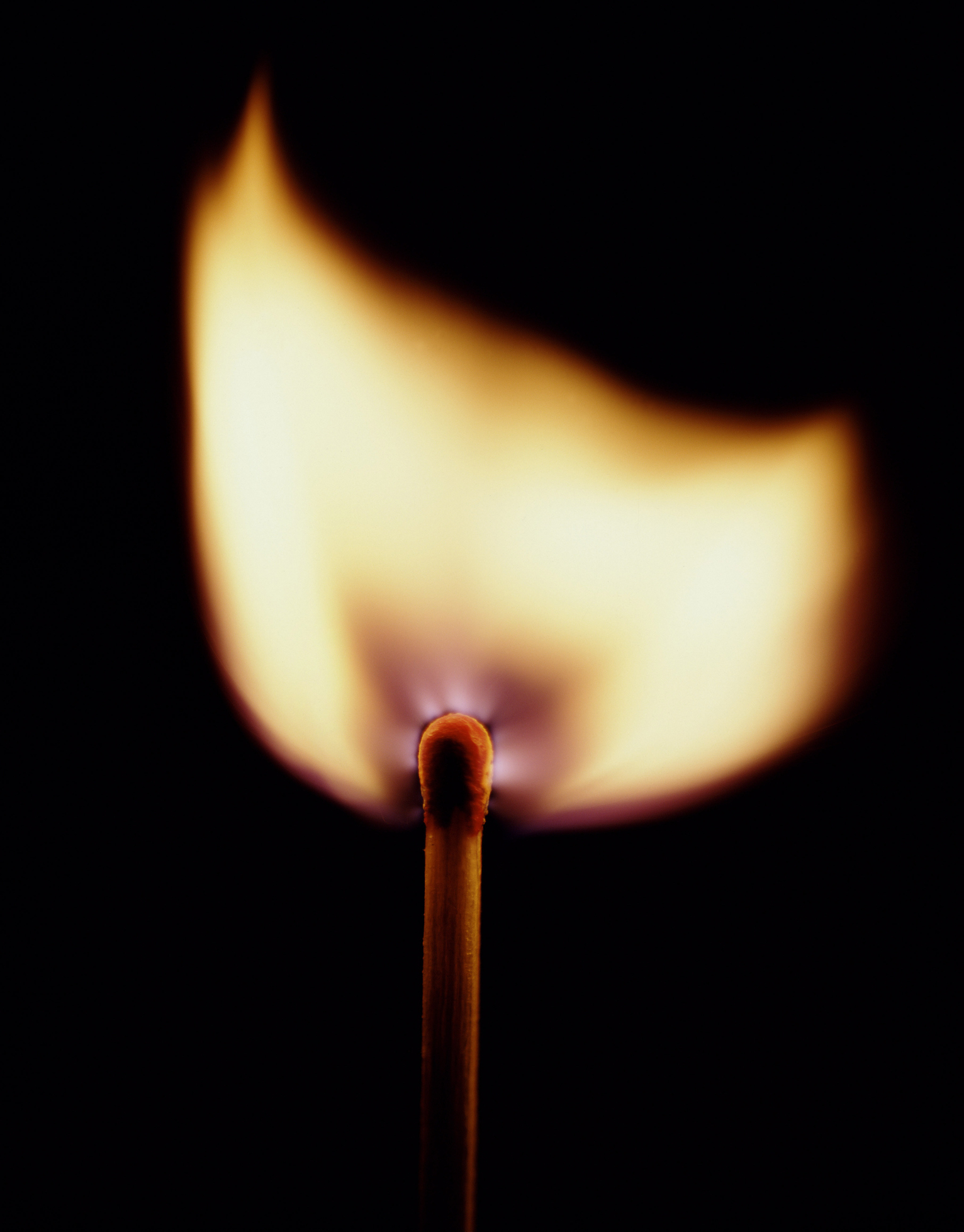 Lit matchstick with a flame against a dark background