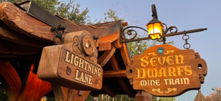 Signage for the &quot;Seven Dwarfs Mine Train&quot; ride and a &quot;Lightning Lane&quot; entrance at a theme park, with rustic wooden decorations