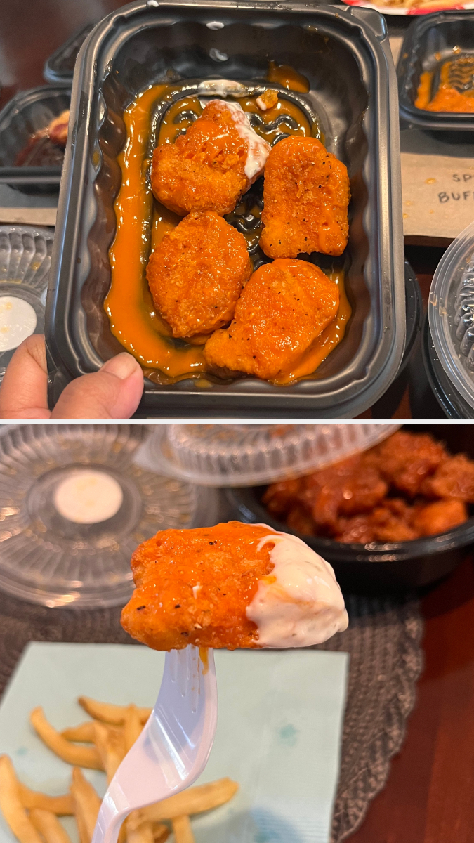 Chicken nuggets, seasoned and coated in sauce, served in a black plastic tray and on a fork dipped in a white sauce. French fries are in the background