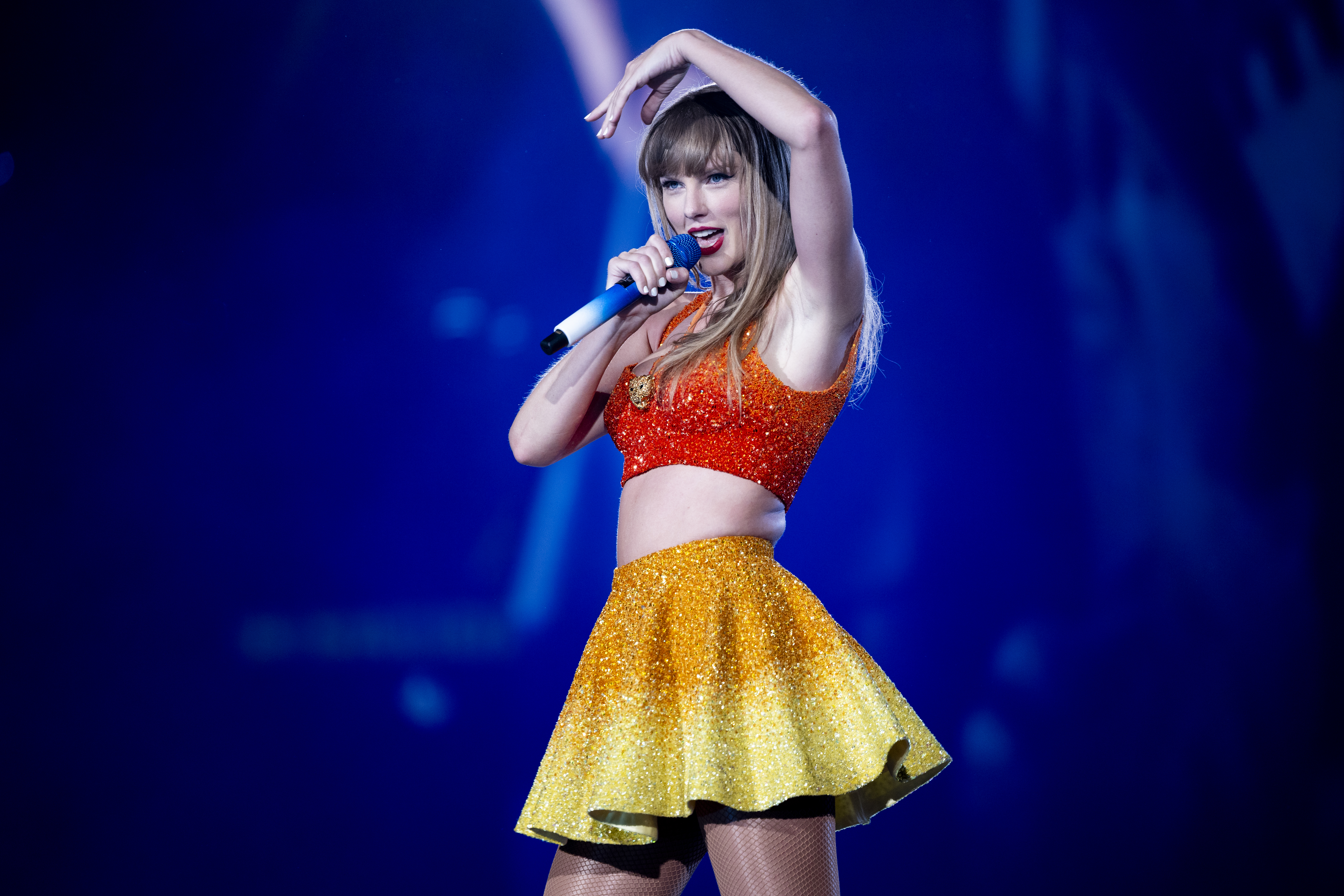 Taylor Swift performs on stage, wearing a sparkling crop top and skirt
