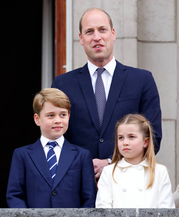 Prince William with Prince George and Princess Charlotte standing on a balcony, all dressed in formal attire