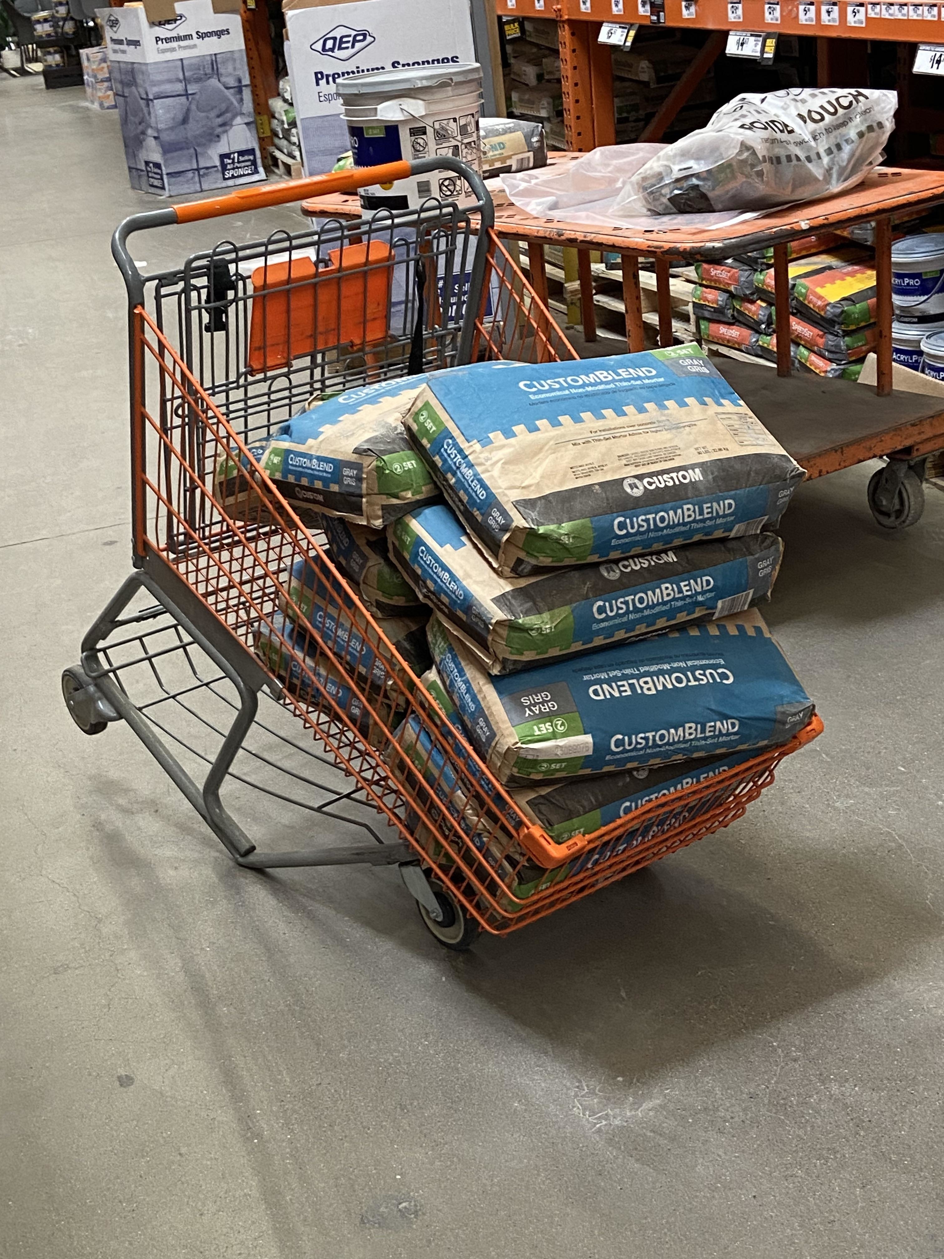 Shopping cart filled with multiple bags of CustomBlend mortar in a hardware store aisle