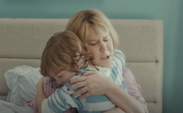 A woman with short hair embraces a young boy wearing a striped shirt