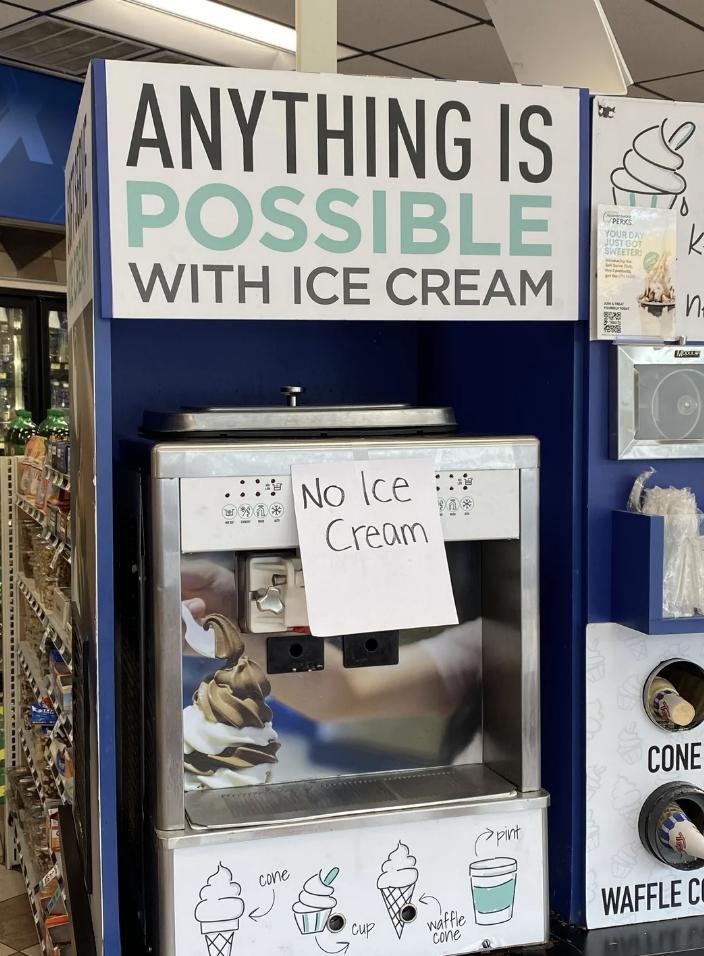 Soft serve ice cream machine at a shop with a &quot;No Ice Cream&quot; sign taped to it. Surrounding signs read &quot;Anything is possible with ice cream&quot; and show different cone options