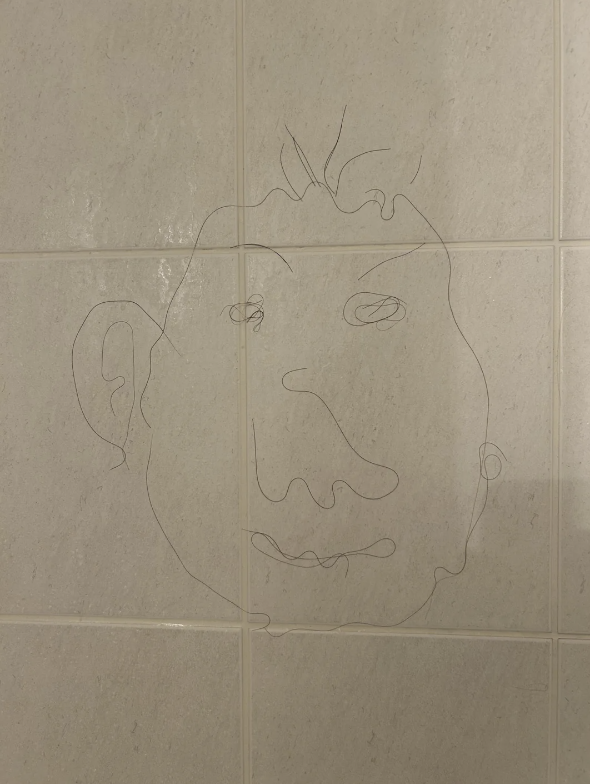 A simple line drawing of a face on tiled wall