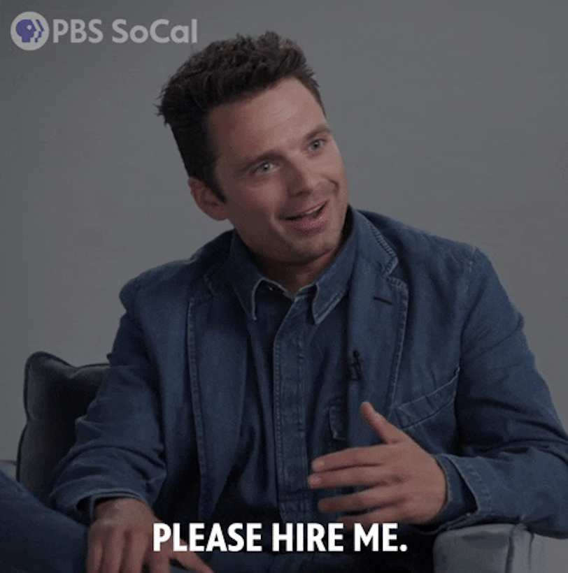 Sebastian Stan smiling and gesturing, wearing a casual denim outfit, with &quot;PBS SoCal&quot; logo and text &quot;PLEASE HIRE ME.&quot;