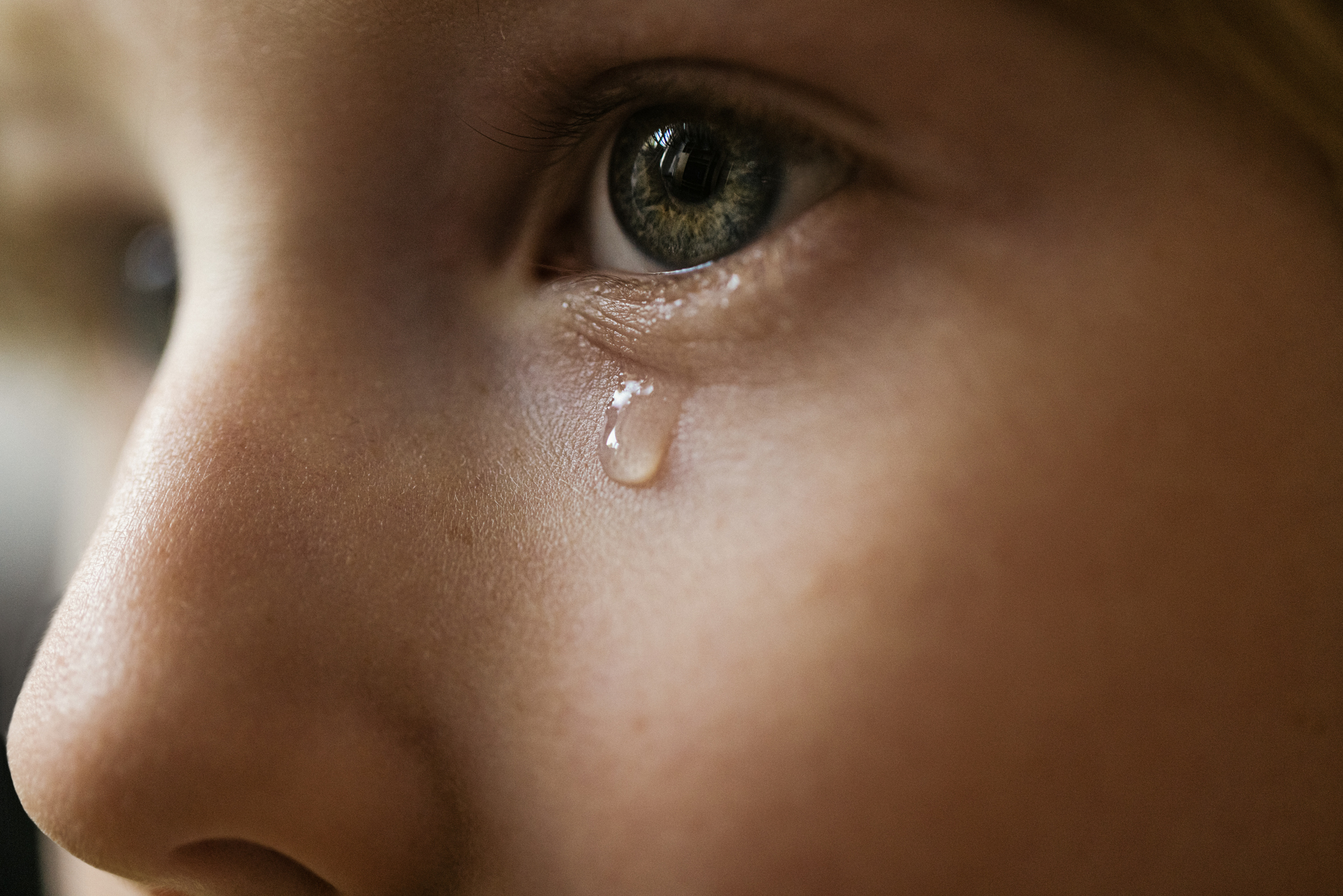 Close-up of a child&#x27;s eye with a tear running down their cheek, depicting emotion