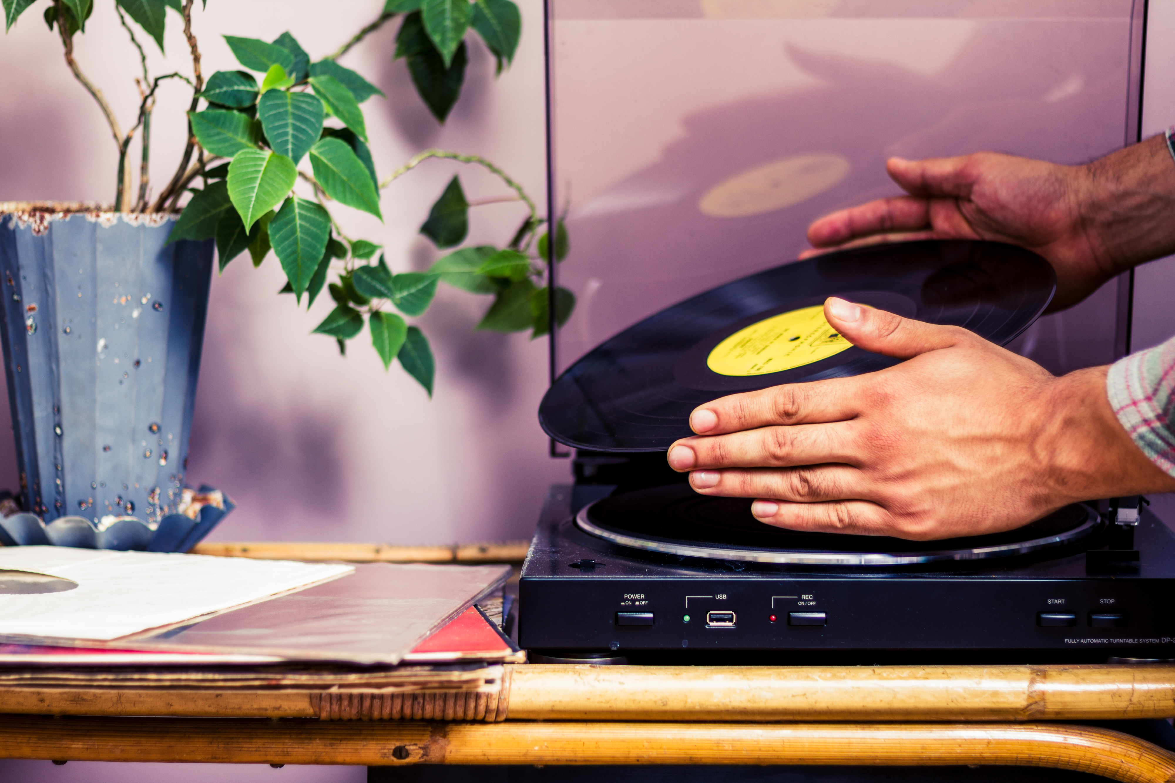 Hands placing a vinyl record onto a turntable