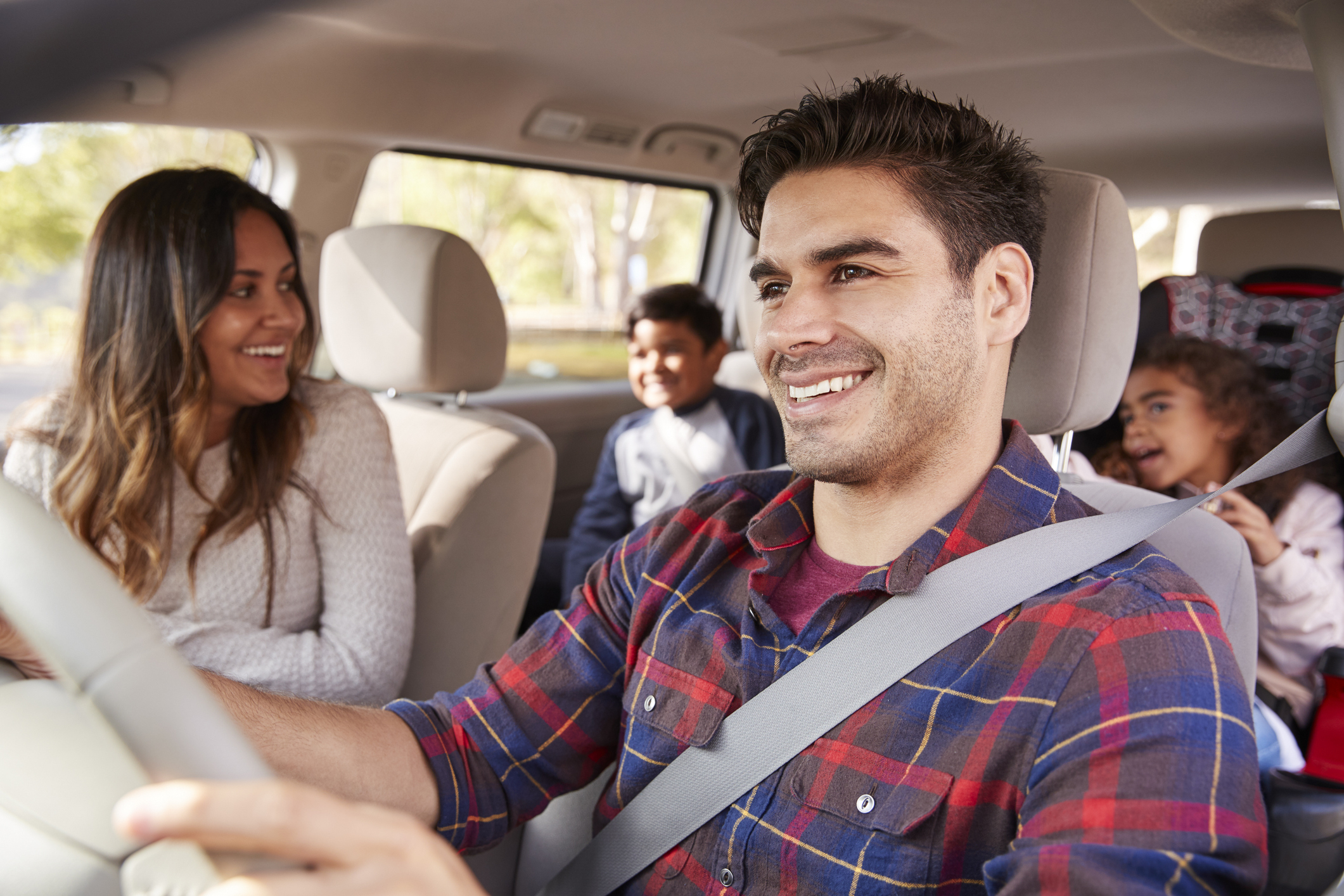 A family of four smiling and talking while seated in a car