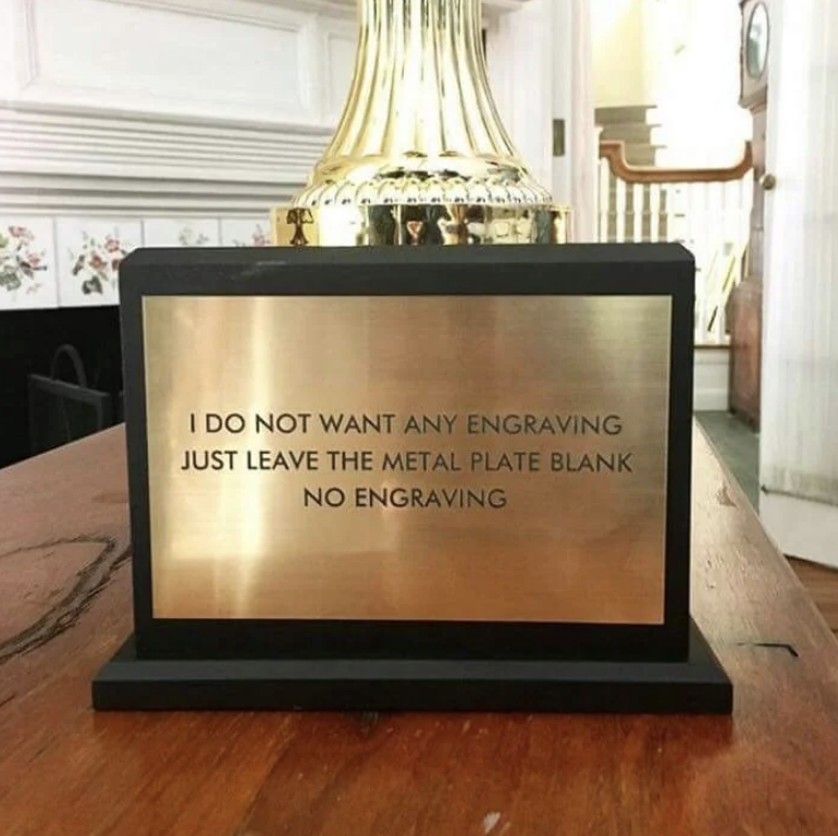 A gold trophy with a metal plate that reads: &quot;I DO NOT WANT ANY ENGRAVING JUST LEAVE THE METAL PLATE BLANK NO ENGRAVING.&quot;