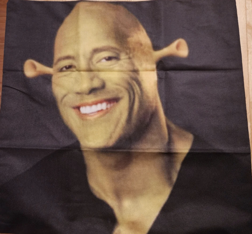 Dwayne &quot;The Rock&quot; Johnson with Shrek&#x27;s green ogre ears and skin, smiling broadly. The image appears on a cloth