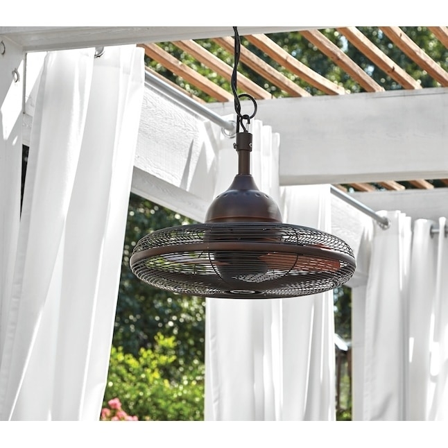 Outdoor fan hanging under a pergola with white drapes in the background