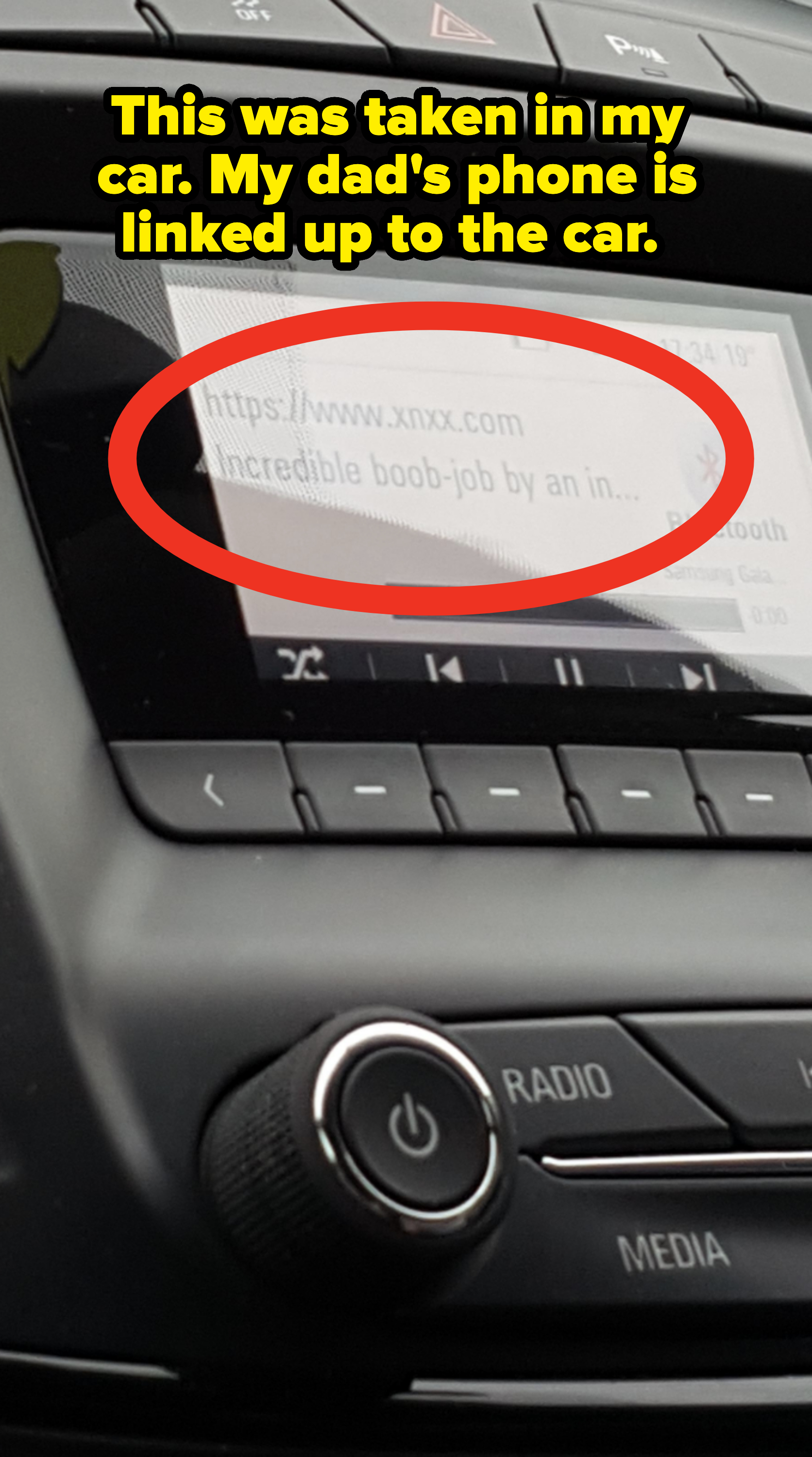 Car dashboard screen displaying inappropriate content with explicit language, showing the title &quot;Incredible boob-job by an in...&quot;. Below, a song is playing via Bluetooth