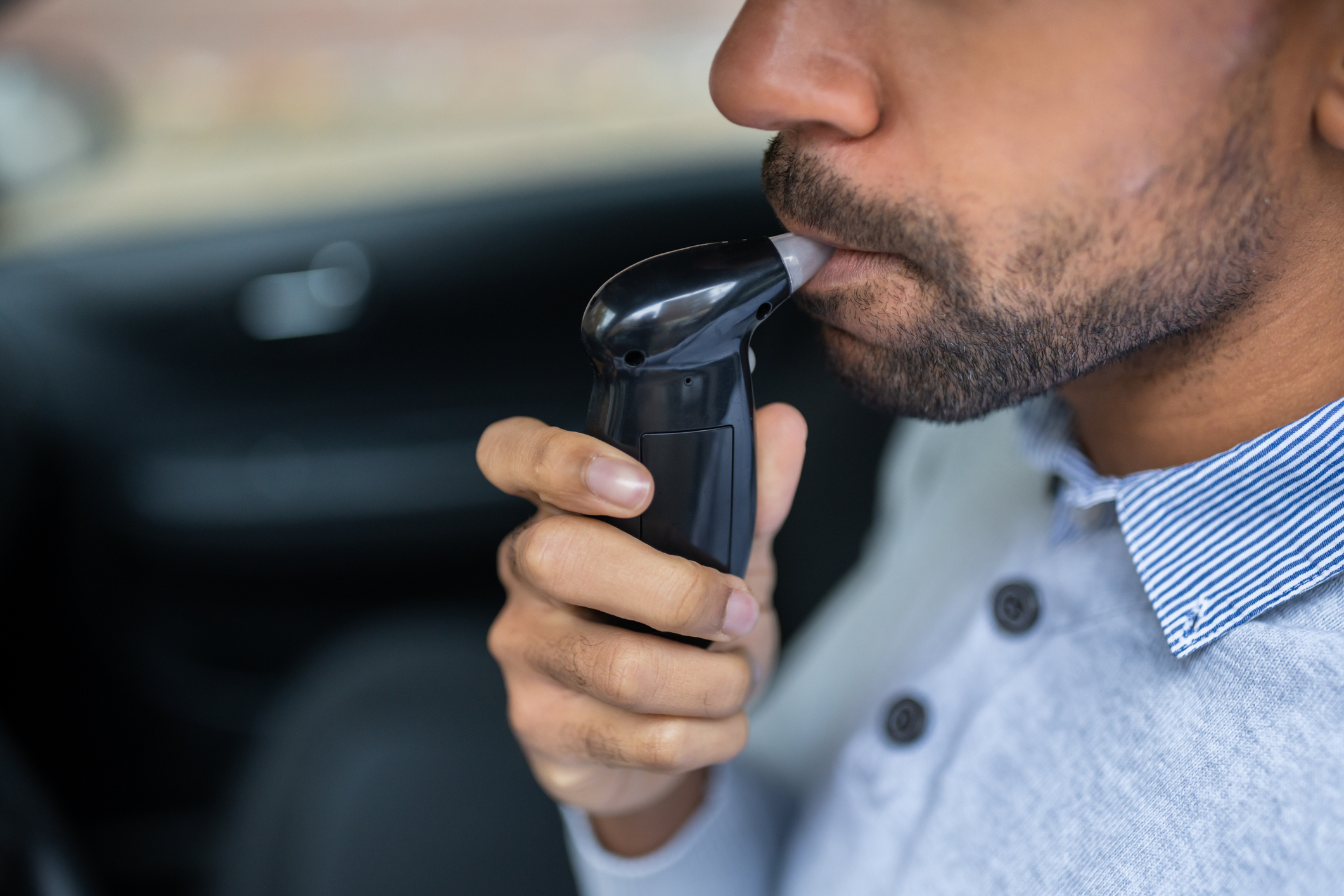 Person using a breathalyzer device in a car