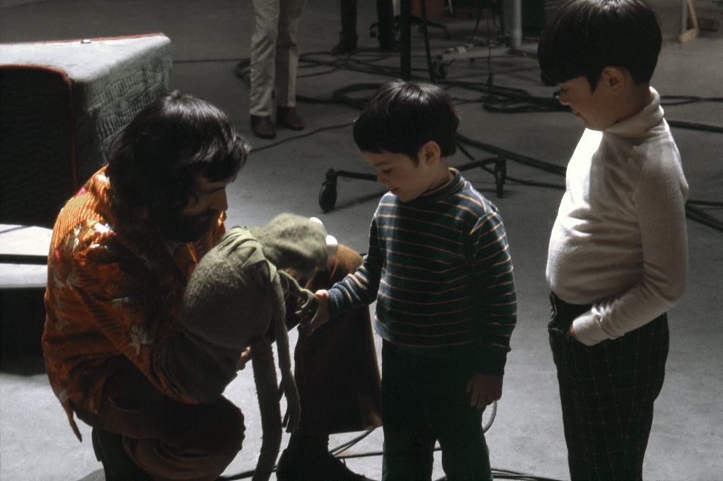Jim Henson shows Kermit the Frog puppet to two young children on a film set