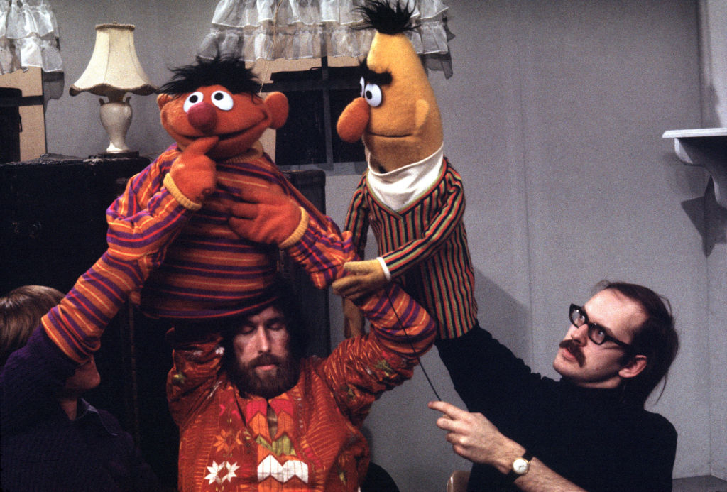 Jim Henson and Frank Oz puppeteering Ernie and Bert from Sesame Street on set, showcasing their iconic puppet characters