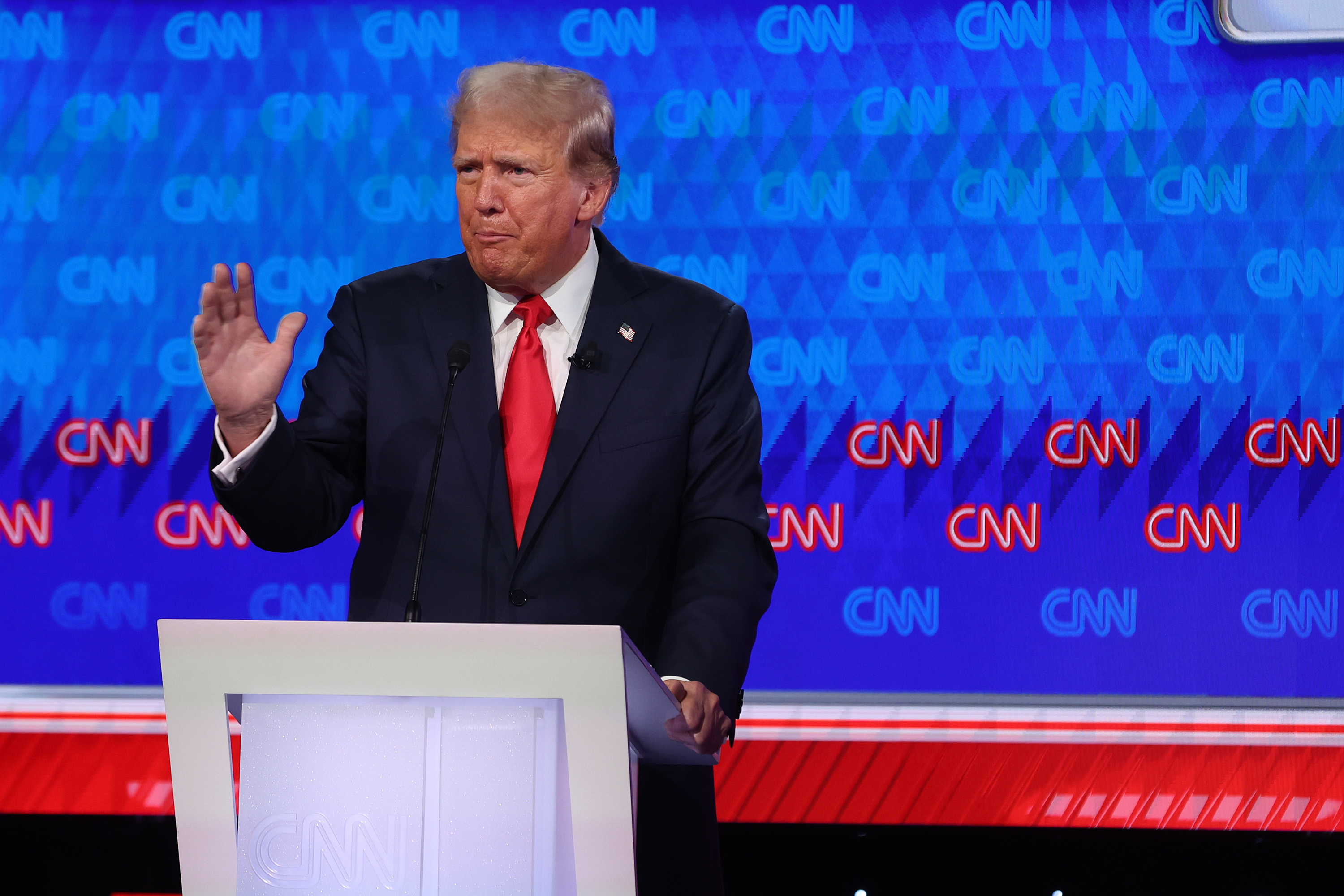 Donald Trump participates in a CNN-hosted event, standing at a podium and gesturing while speaking