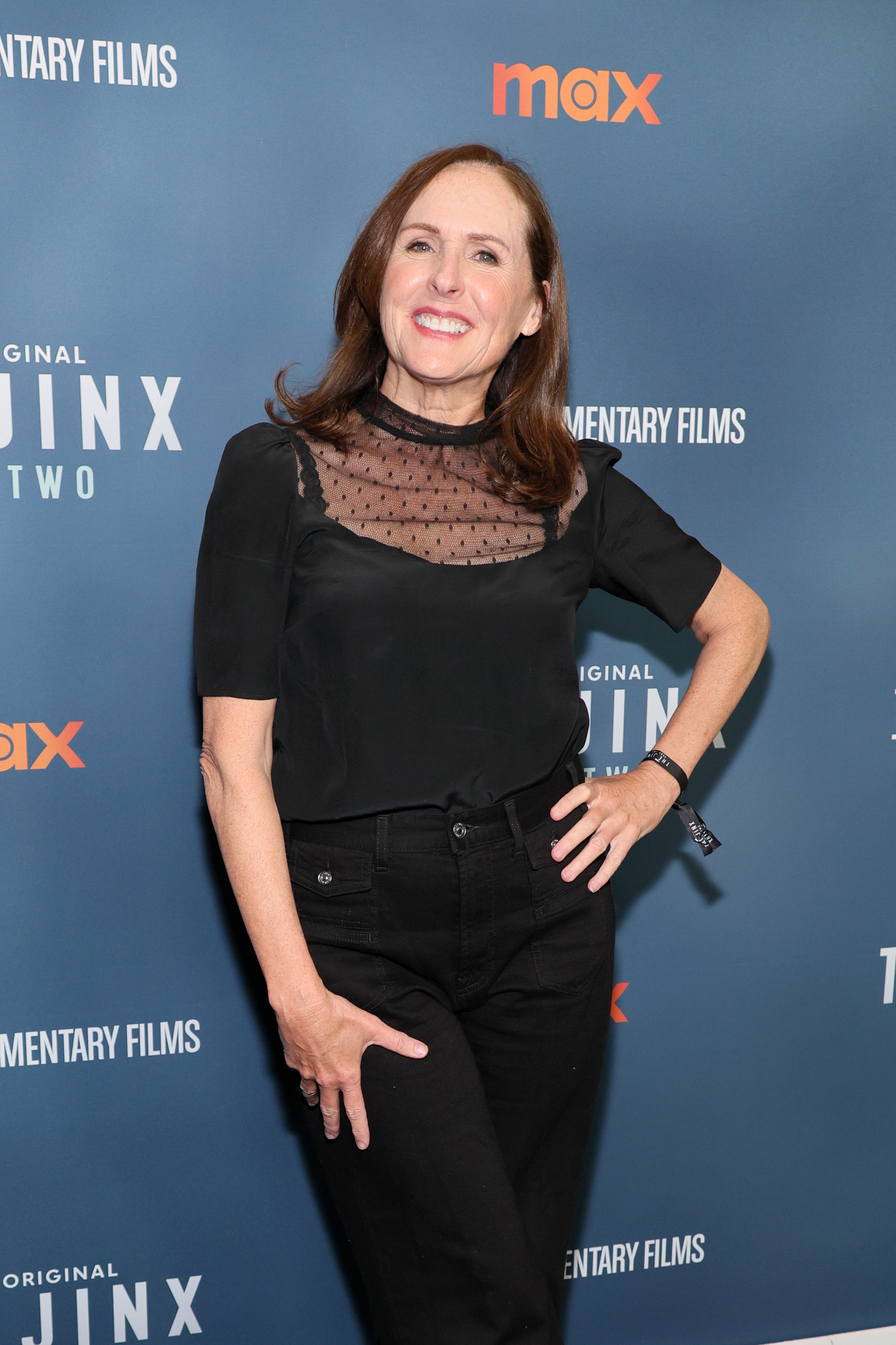 Molly Shannon posing on the red carpet, wearing a sheer black top and black pants, at an event for Max Original&#x27;s documentary films