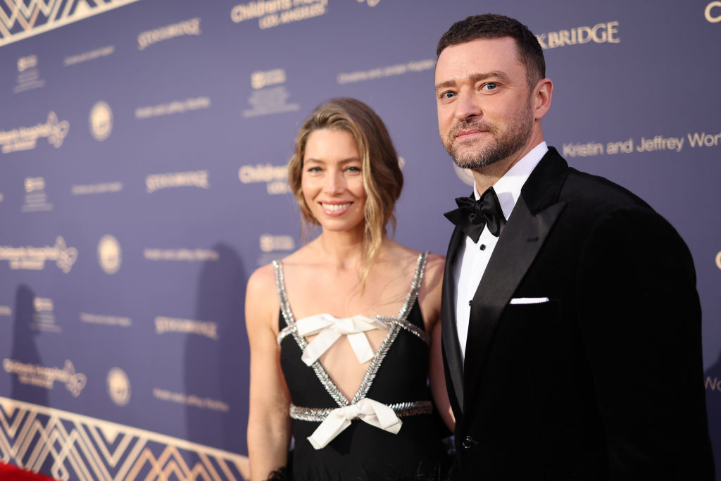 Jessica Biel, in a black dress with white bow accents, and Justin Timberlake, in a black tuxedo, pose on a red carpet at an event