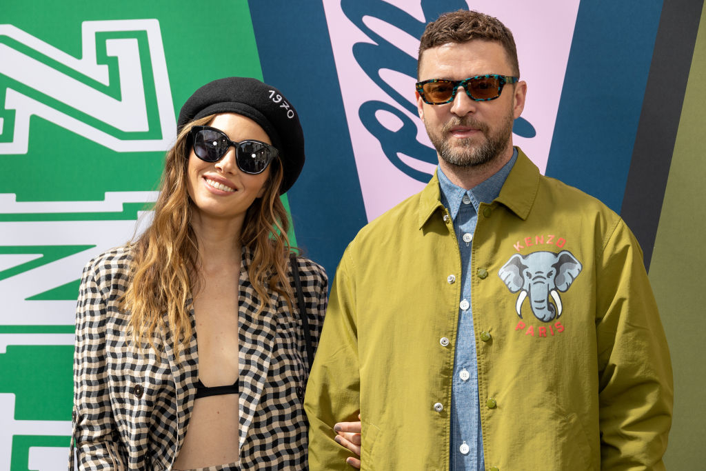 Jessica Biel in a checkered jacket and black beret, and Justin Timberlake in a green jacket with sunglasses at an event