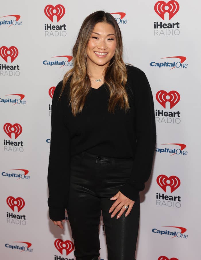 Jenna Ushkowitz posing at an iHeartRadio event, wearing a black sweater and black pants