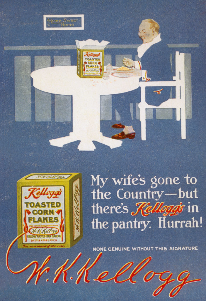 An advertisement featuring W.K. Kellogg at a table beside a Kellogg&#x27;s Toasted Corn Flakes box. Text: &quot;My wife&#x27;s gone to the Country – but there&#x27;s Kellogg&#x27;s in the pantry. Hurrah!&quot;