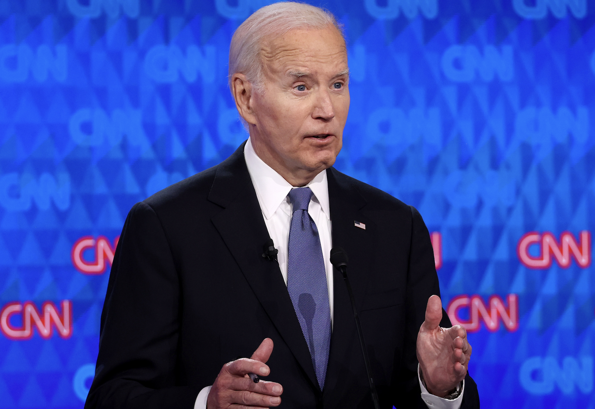 Joe Biden speaking during a CNN event, gesturing with his hands, wearing a suit and tie against a CNN-branded backdrop