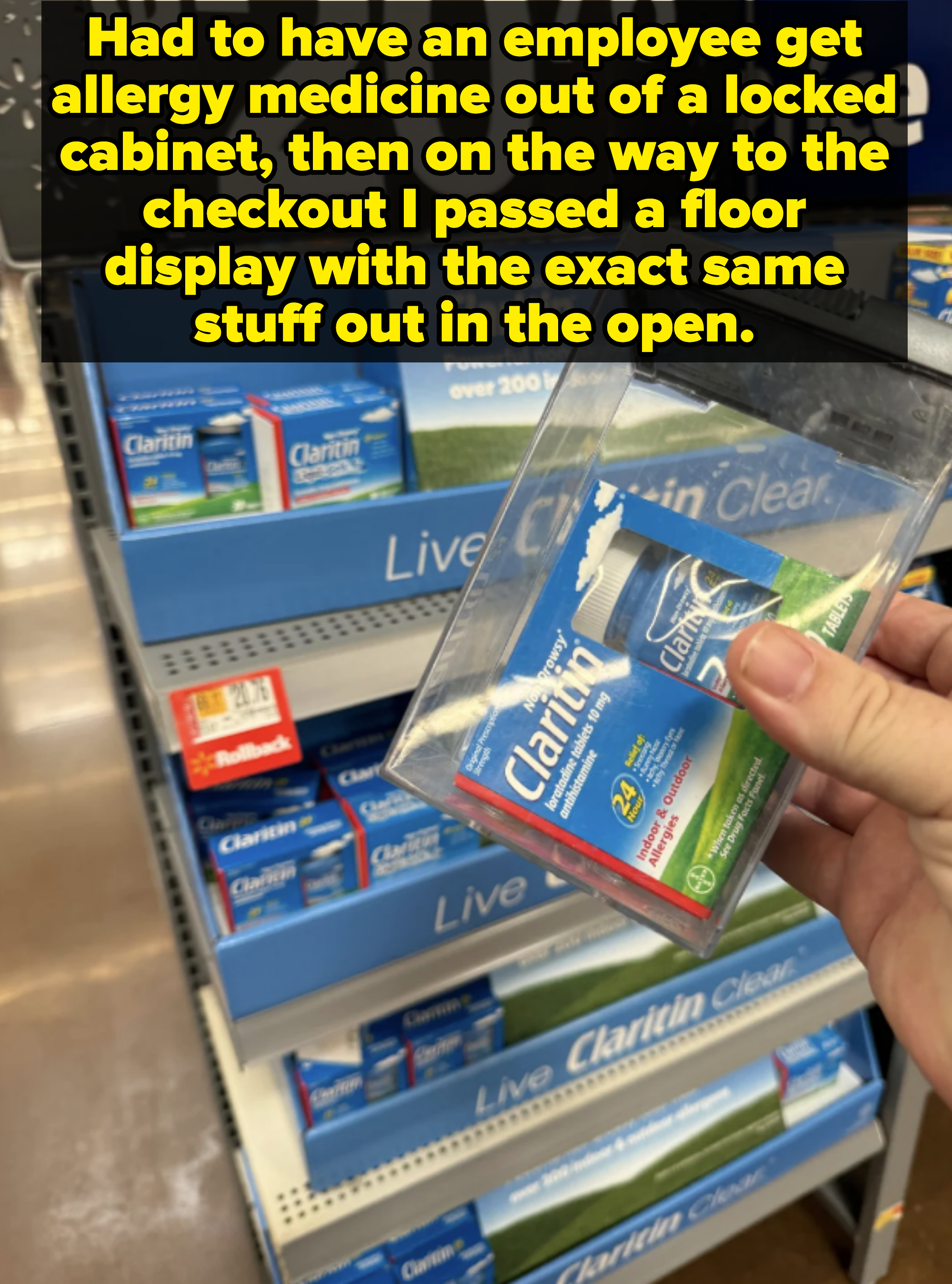 Hand holding a Claritin box in front of a store display filled with Claritin boxes. A sign above reads &quot;-20%&quot;