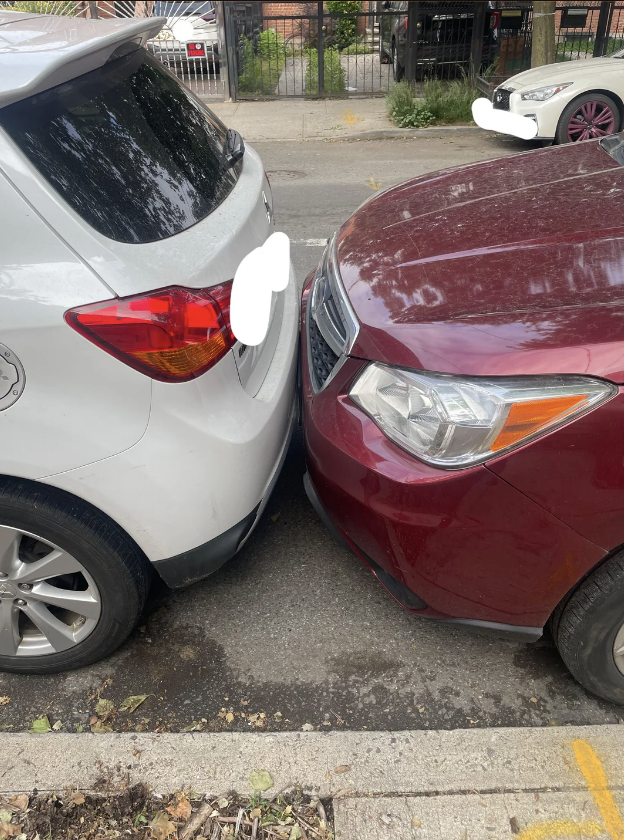 Two cars are shown parked bumper to bumper on the street, one white and one red, touching each other closely with no visible space between