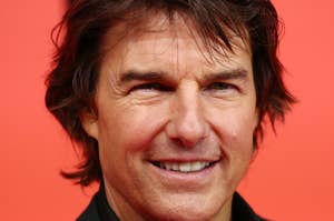 Tom Cruise smiles at the camera on a red carpet