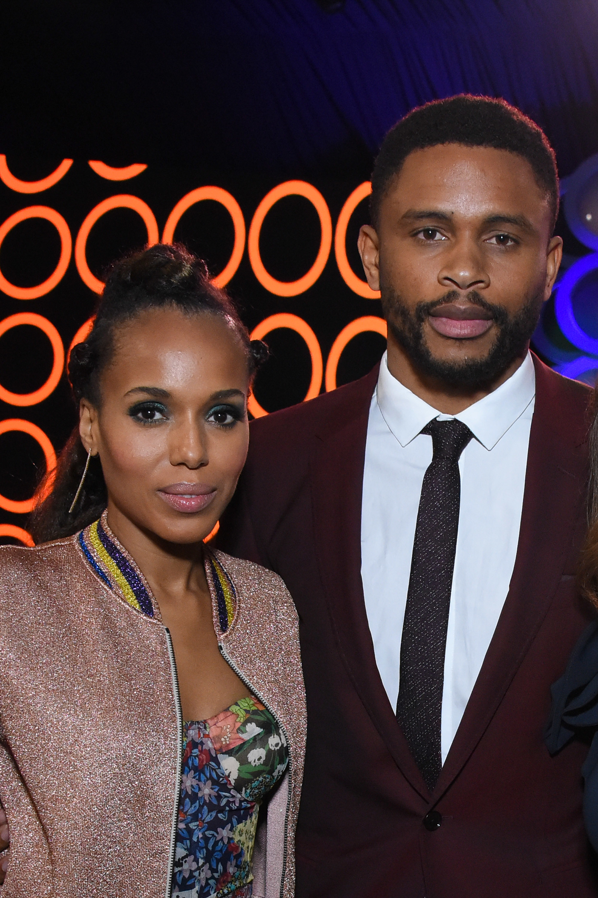 Kerry Washington in a patterned dress and a shimmery jacket, standing next to Nnamdi Asomugha who is wearing a suit and a tie