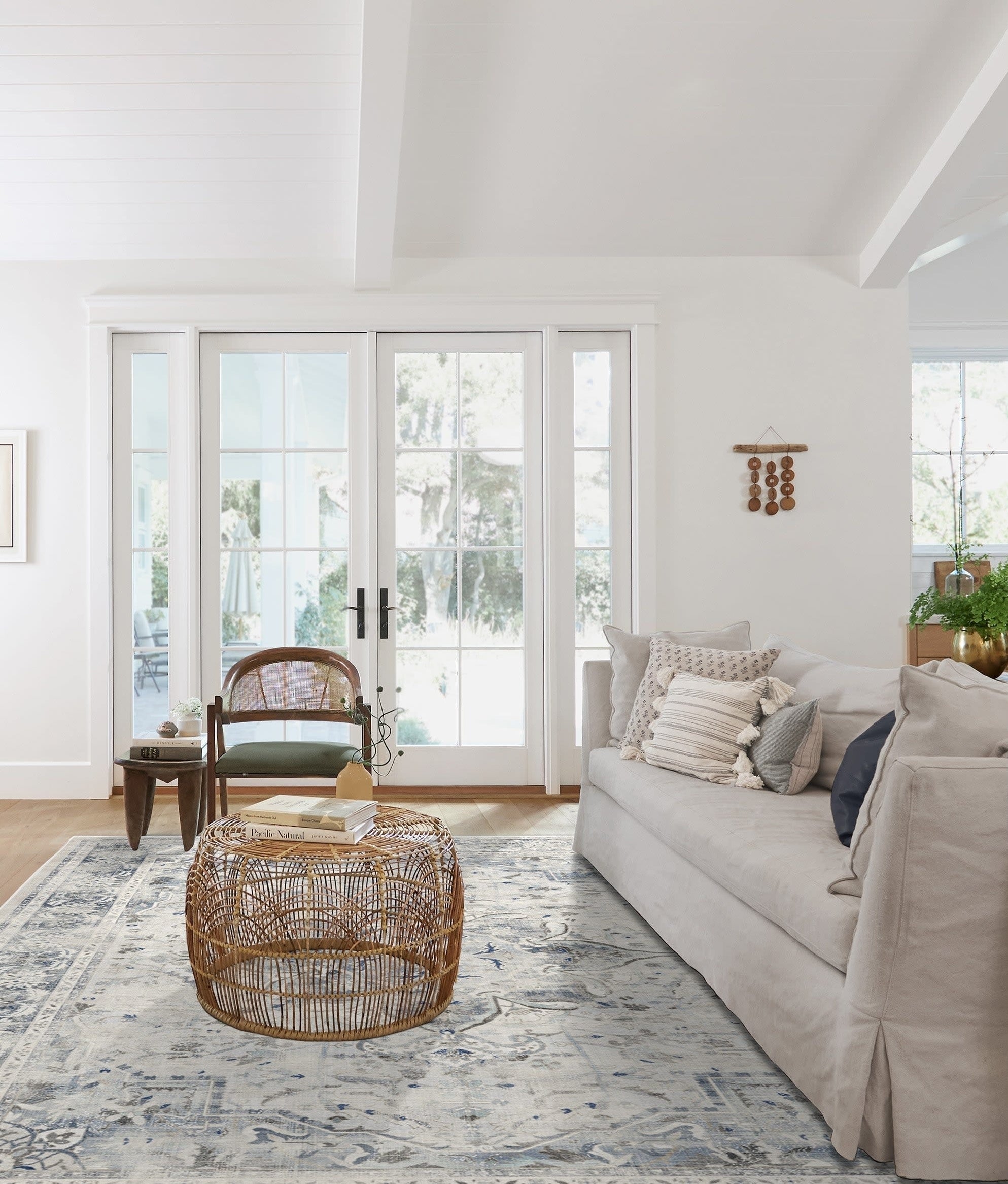 Living room with a light-colored couch, a wicker coffee table, and a patterned rug