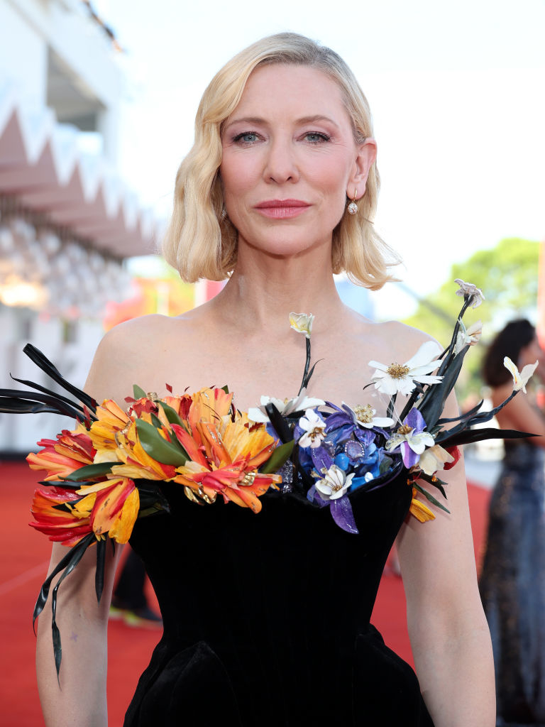 Cate Blanchett on the red carpet wearing a strapless black dress adorned with vibrant floral accents on the bodice