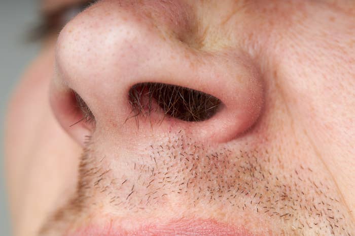 Close-up of a man&#x27;s nostrils and upper lip, showing nose hair and stubble