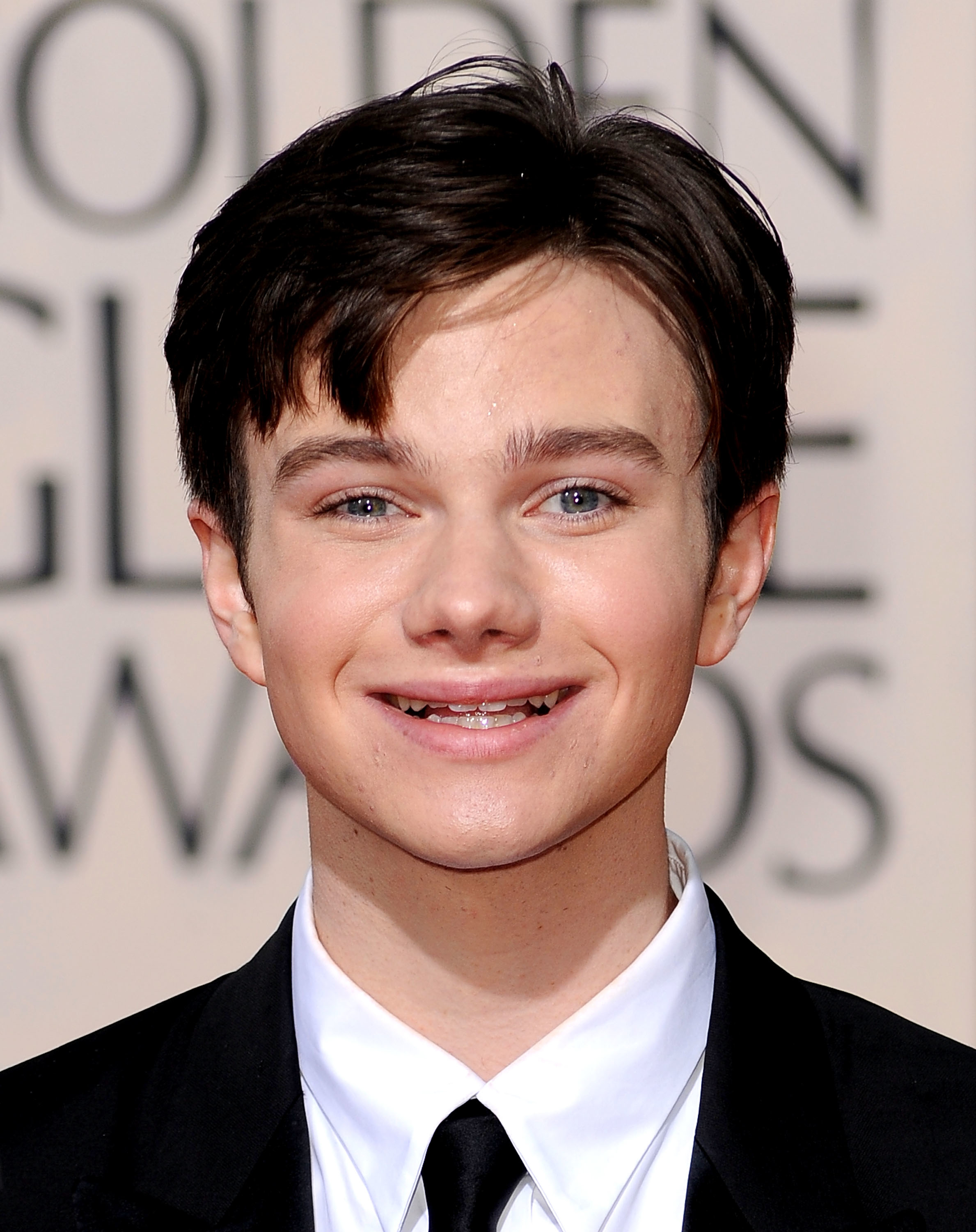 Chris Colfer at the Golden Globe Awards, smiling and dressed in a suit and tie