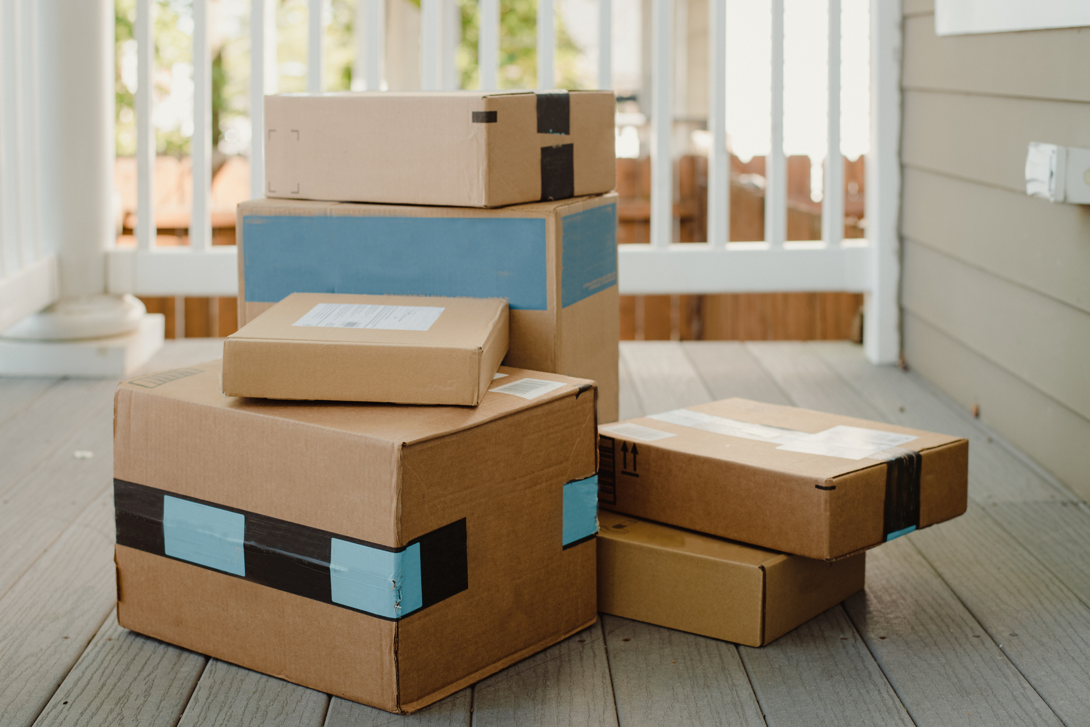 Several cardboard delivery boxes of varying sizes are stacked on a porch