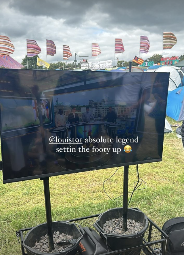 TV screen in a festival setting with text, &quot;@louisT91 absolute legend settin the footy up ?&quot;. Flags and tents in background