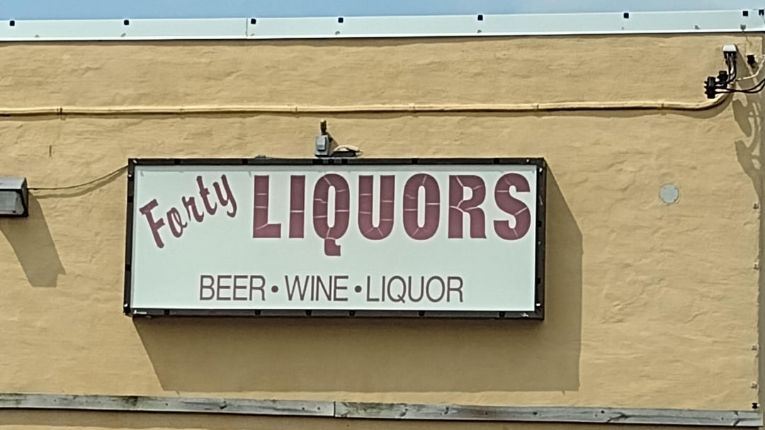 The sign reads: Forty Liquors, offering beer, wine, and liquor; the cursive &quot;A&quot; in Forty makes it appear that the shop is called &quot;Farty Liquors&quot;