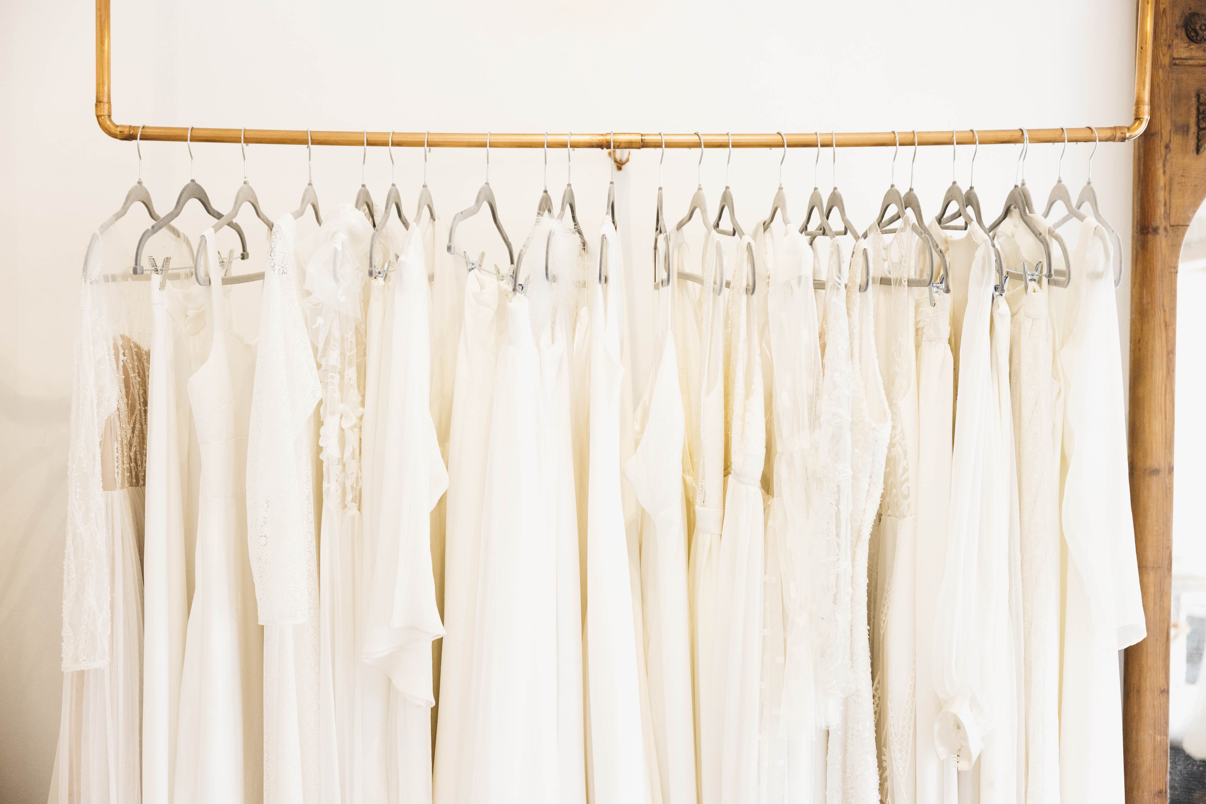Clothing rack displaying a variety of elegant white wedding dresses hung on hangers. No people or specific text visible in the image