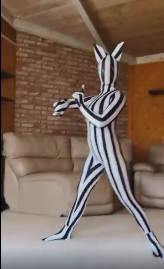 Person in a vertical-striped full-body suit, resembling a zebra, holding and playing a violin in a living room