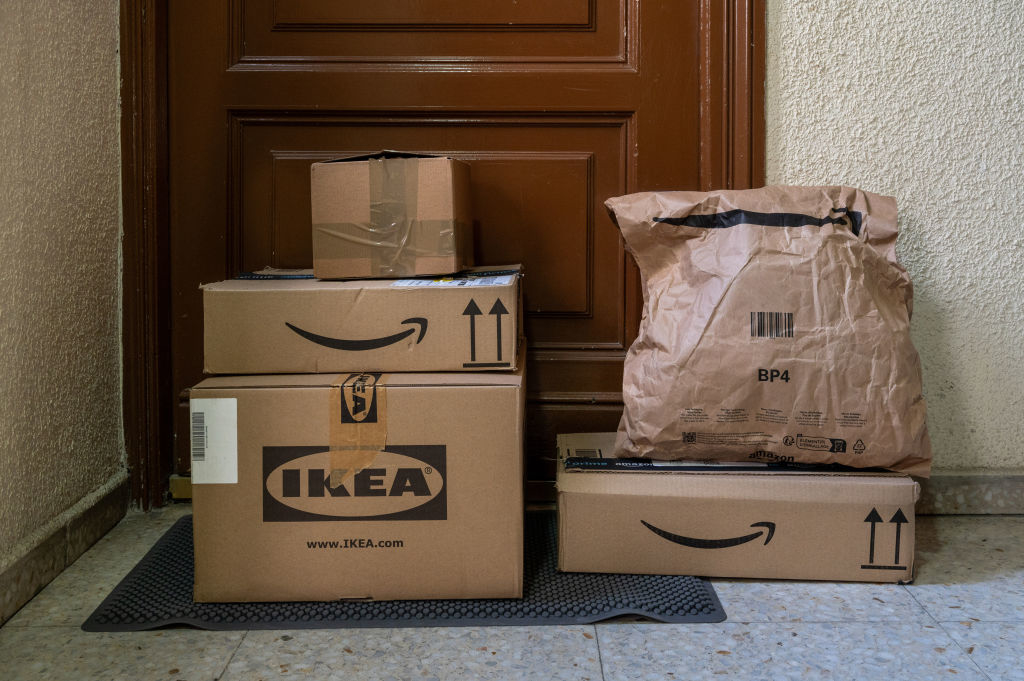 Several packages from Amazon and IKEA placed on a doormat in front of a closed door