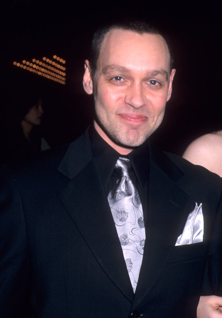 Man wearing a black suit with a patterned tie and pocket square, smiling at the camera. Event appears to be formal. Names of persons in the image are unknown