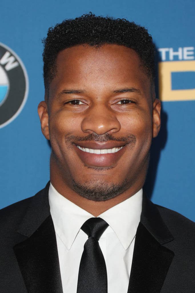 A smiling man in a suit and tie poses in front of a blue backdrop