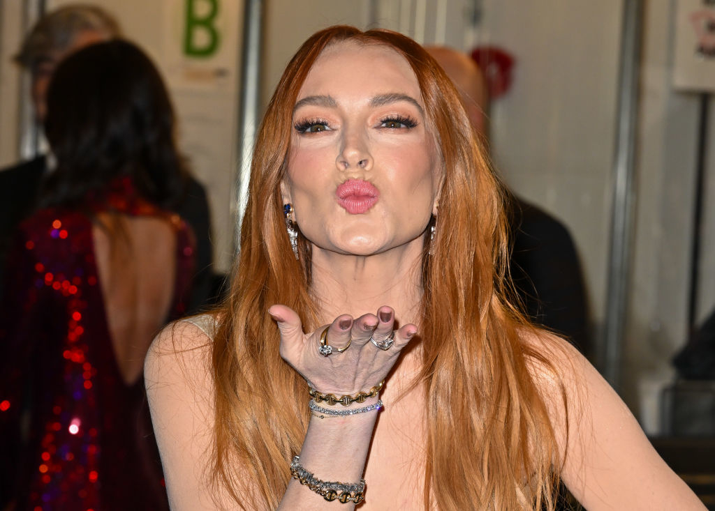 Lindsay Lohan blows a kiss towards the camera, wearing a sleeveless top and multiple bracelets on her left wrist