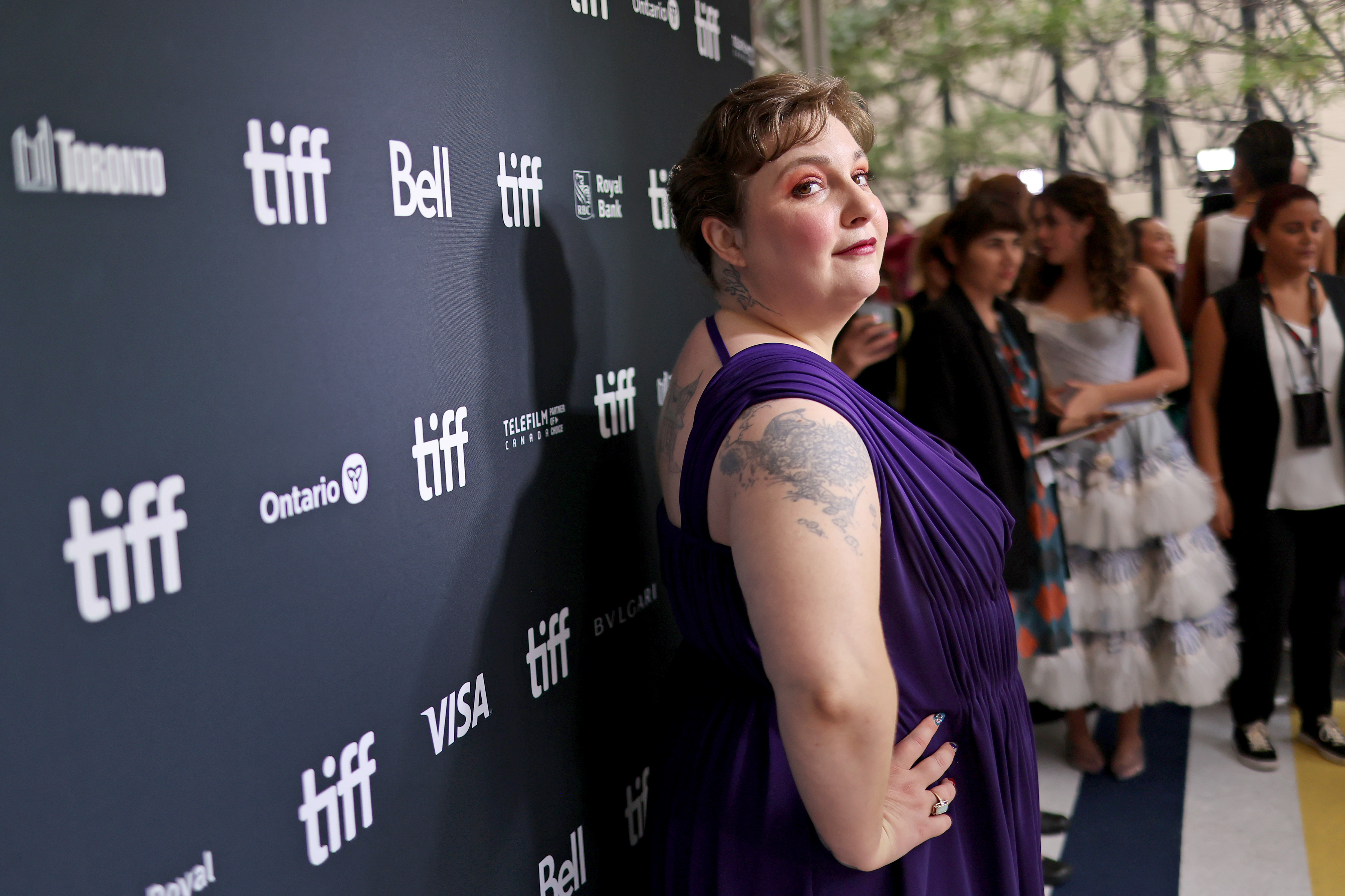 Lena Dunham poses on the Toronto International Film Festival red carpet in an elegant, pleated, sleeveless dress