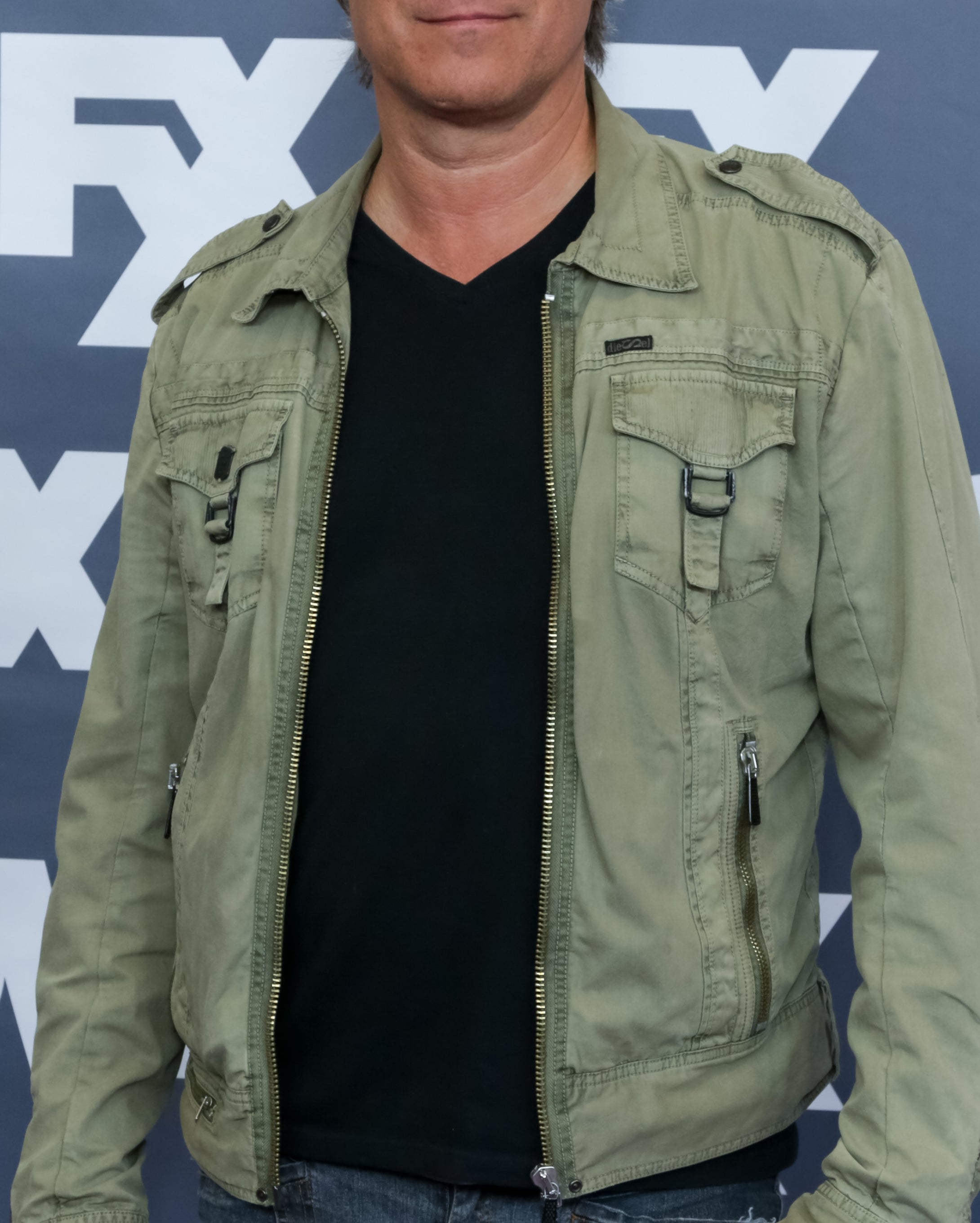 John Corbett in a casual outfit with a green jacket and jeans at an FX event